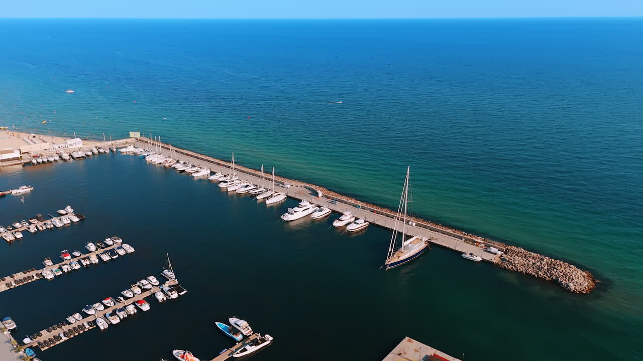 Sailboats at calm marina. Sailboats rest peacefully at a coastal marina during bright daylight, with calm waters and clear skies above