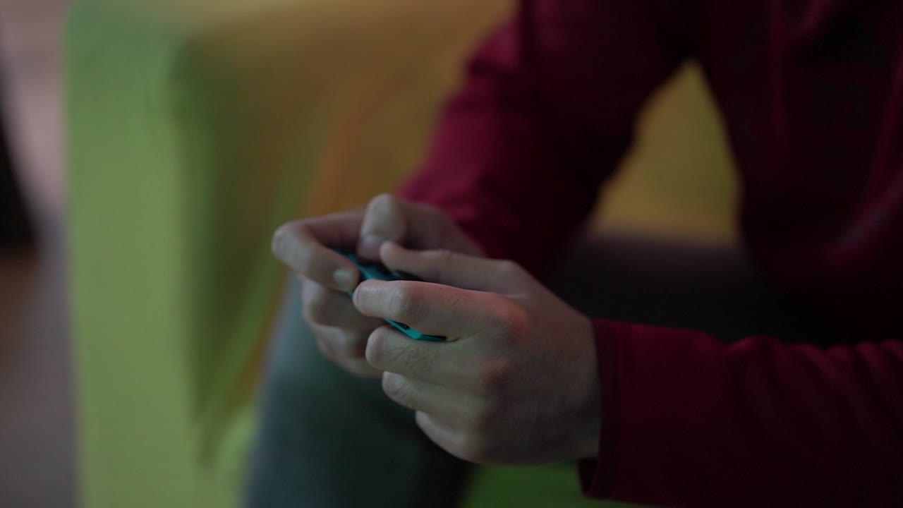 Caucasian fingers play and maneuver turquoise game controller device, close up shallow focus