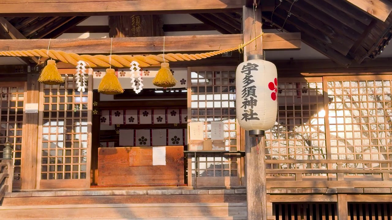 Static shot of a traditional Japanese Shinto shrine with warm golden hour sunlight illuminating wood