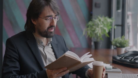 man reading a book and drinking coffee in a cafe