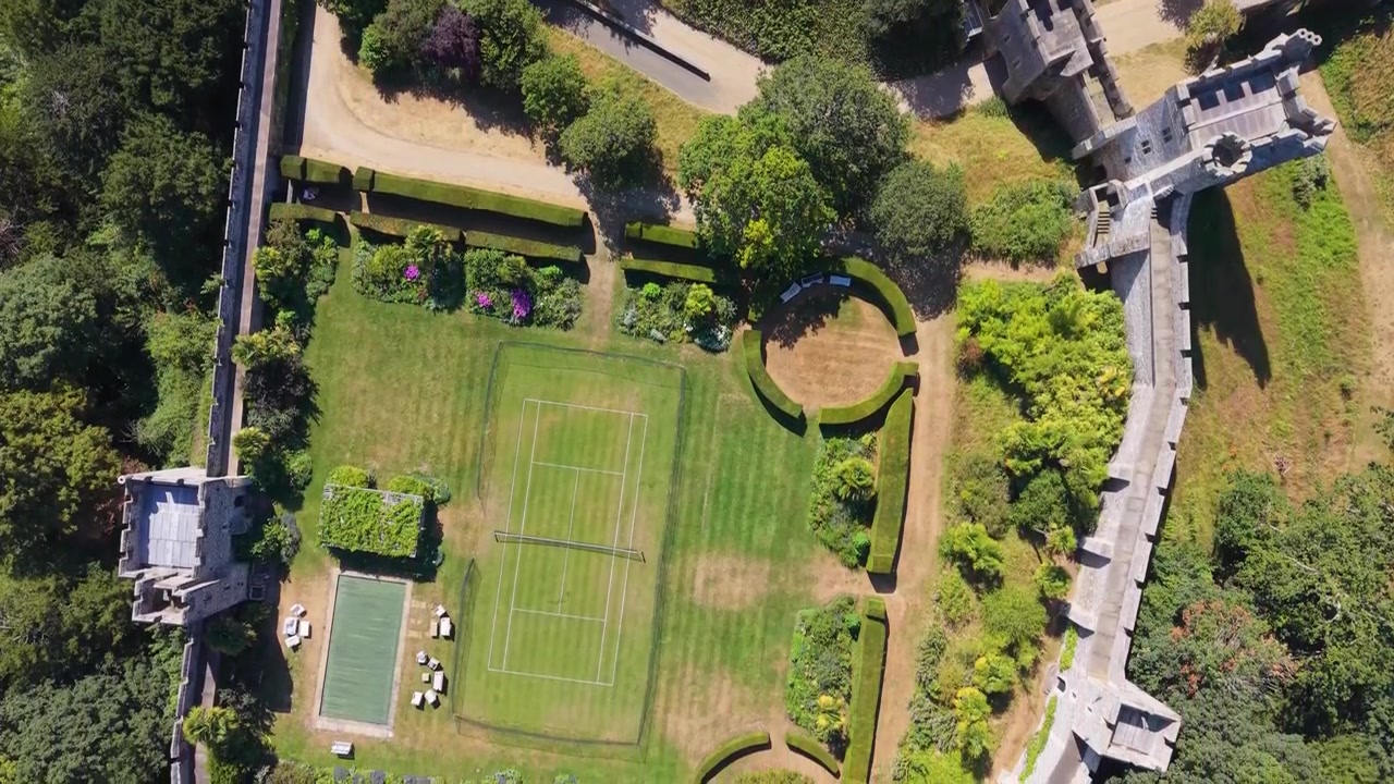 Arundel Castle top-down aerial reverse pan over medieval turrets, fortified walls and inner courtyard, revealing historic architecture, rooftops, shadows and garden patterns in England.