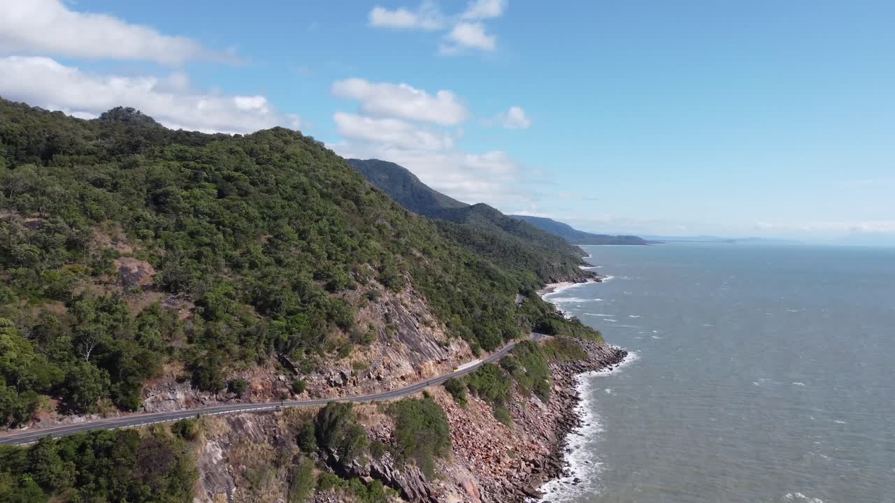 Vista aérea 4K de uma costa acidentada perto do Oceano Pacífico com uma rodovia costeira na Austrália.