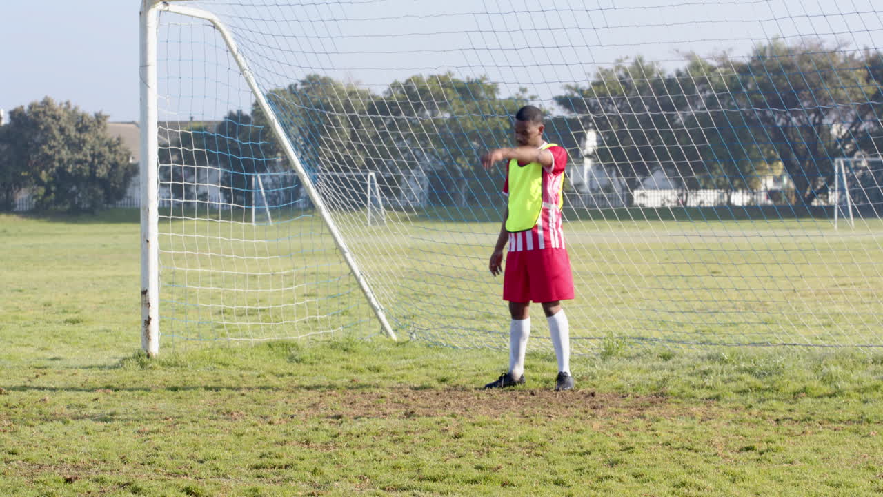 Goalkeeper in soccer uniform standing in front of goalpost on field