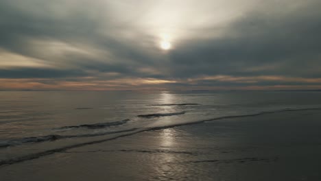 Luftaufnahme-Des-Dramatischen-Himmels-über-Dem-Strand,-Der-Sich-Schnell-Ins-Meer-Bewegt