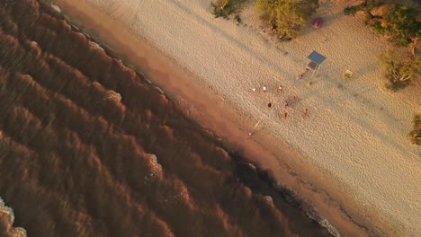 toma aérea de arriba hacia abajo de personas jugando voleibol en la playa de arena durante la puesta de sol