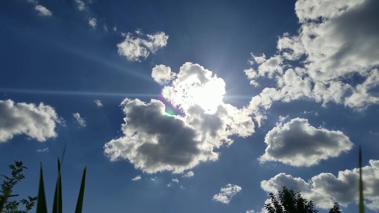 Il sole splendente splende attraverso le nuvole bianche nel cielo blu