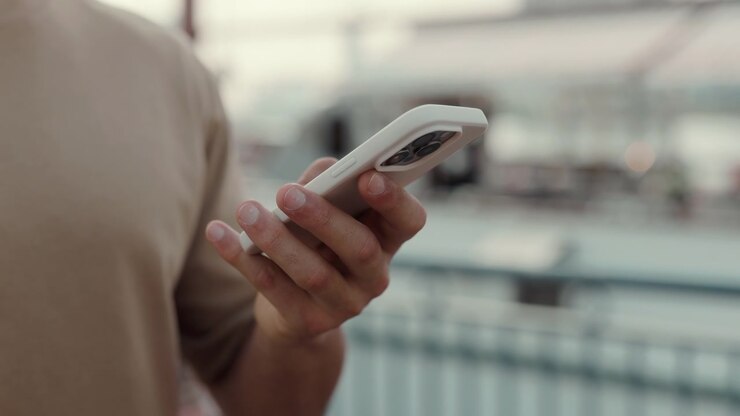 Mano di una persona che tiene uno smartphone con sfondo sfocato