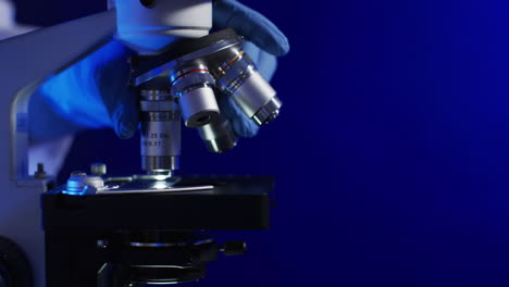 Video-of-close-up-of-laboratory-microscope-with-copy-space-on-blue-background