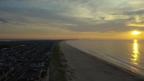high aerial view of beachside suburb and calm beach at sunset, panorama