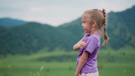 Adorable-girl-with-plait-shows-thumb-up-in-mountain-valley