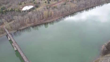 3-3-Blick-Aus-Der-Vogelperspektive-Fliegen-über-Die-Fußgänger-Fachwerkbrücke-Im-Park-über-Den-Teich-Und-Einen-Verschmutzten-Fluss-Im-Herbst,-Ohne-Dass-Jemand-An-Einem-Herbstnachmittag-Mit-Gepflegten-Wegen,-Kiefern,-Ahorn,-Eiche-Und-Birke-In-Sicht-Ist