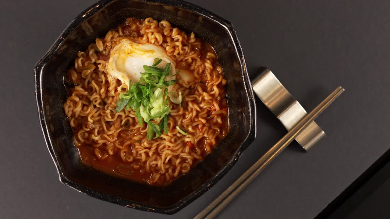 A video of chewy stir-fried ramyun coated in spicy seasoning, topped with a soft-boiled egg and scallions for rich flavor. 매콤한 양념을 입힌 쫄깃한 라면볶음에 반숙 계란과 파를 얹어 풍부한 맛을 내는 영상입니다.