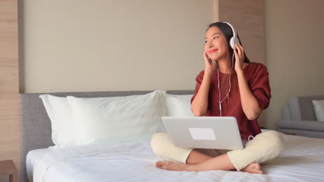 smiling asia woman listen music from laptop with headphones and moving head in rhythm of song, static with copy space