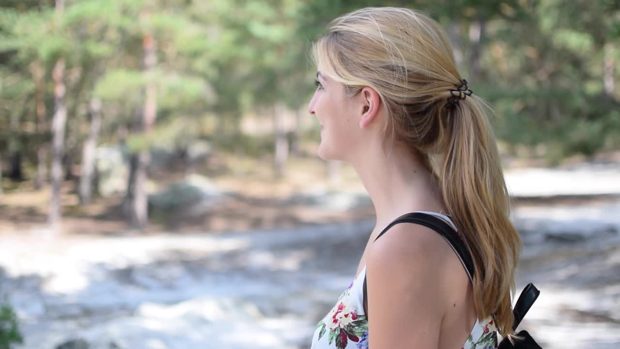 Young female hiker  smiles at camera then walks away