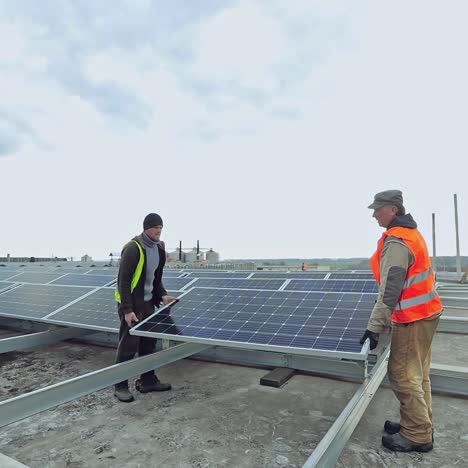 workers install new solar panels. two technician men installing photovoltaic panels on metal basis. sustainable and renewable energy.