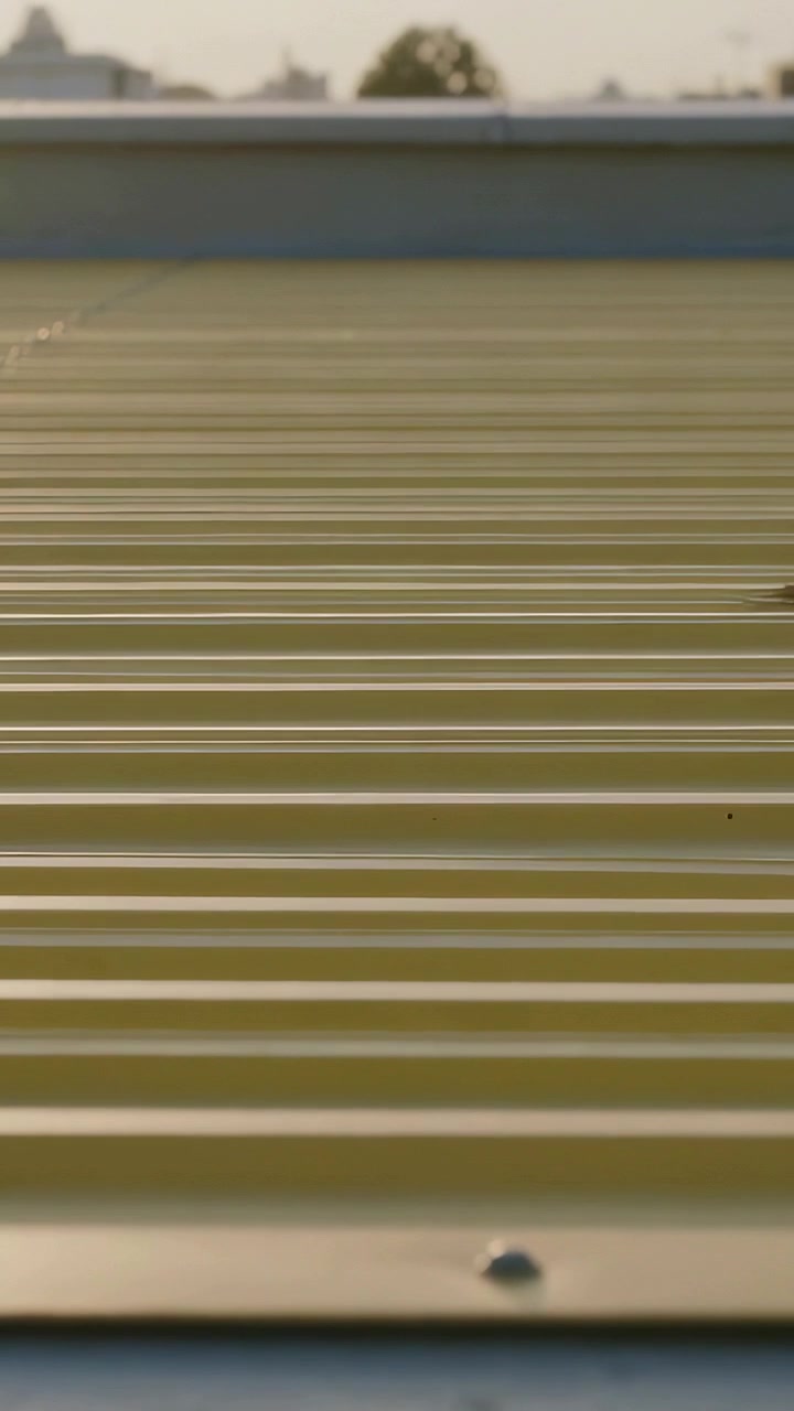 Vertical video: Sliding small object entering right, moving across corrugated roof, showing rivet