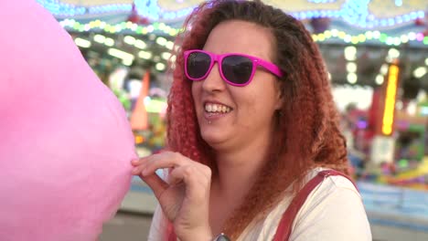 happy woman with cotton candy dances at the fair