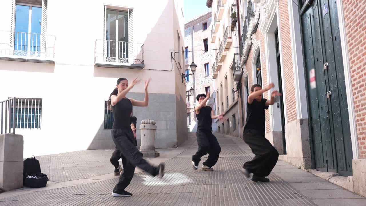 Giovani ballerini che eseguono una street dance sincronizzata in un vicolo urbano