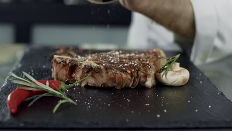 Chef-peppering-grilled-meat-at-cut-board.-Man-hands-pepper-steak-in-slow-motion