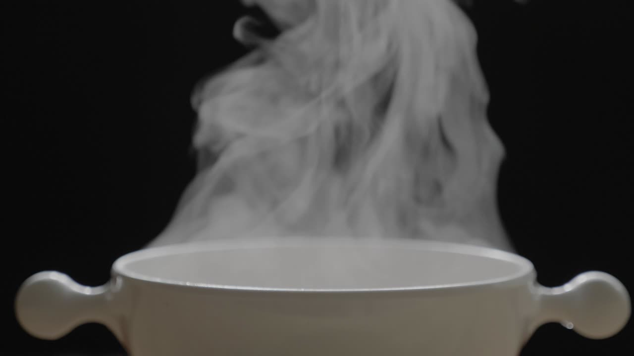 el té caliente en la taza blanca tiene efecto de humo y vapor blanco en el fondo negro.
