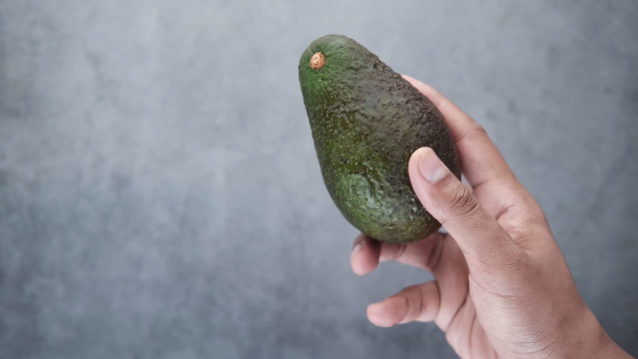 Mano che tiene un avocado