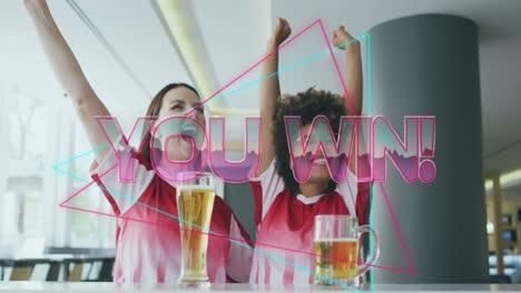 Animation-of-you-win-text-over-happy-diverse-female-friends-raising-hands-and-drinking-beer