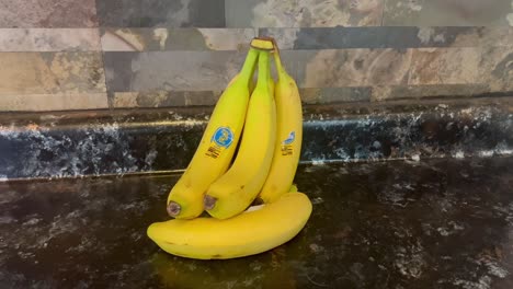 bunch of bananas on black kitchen countertop and stone backsplash