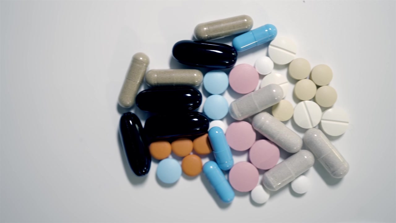 Pile of assorted medical tablets and capsules close up top view