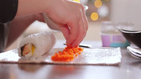 hacer sushi en la cocina de casa. manos de mujer enrollando sushi casero.