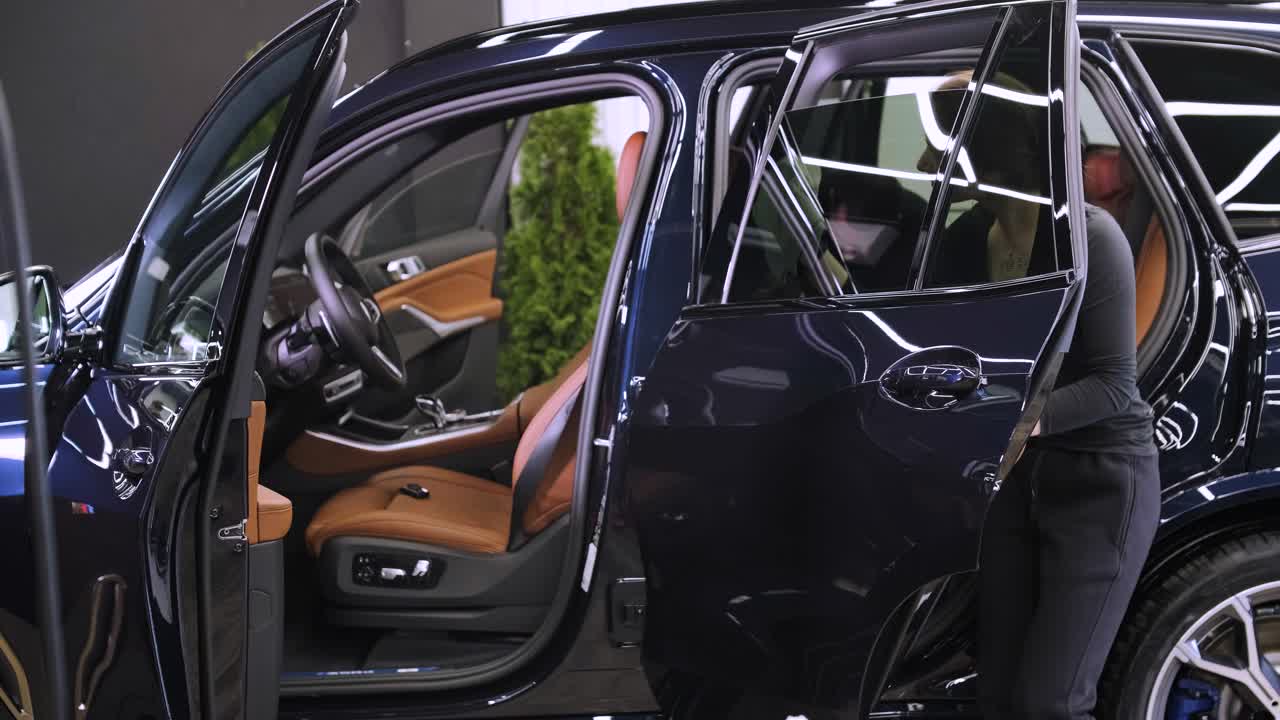 el lavador de coches profesional con guantes negros limpia el coche después de lavar y forrar la cerámica. conceptos de: trabajo profesional, varias herramientas de lavado, limpieza para brillar.