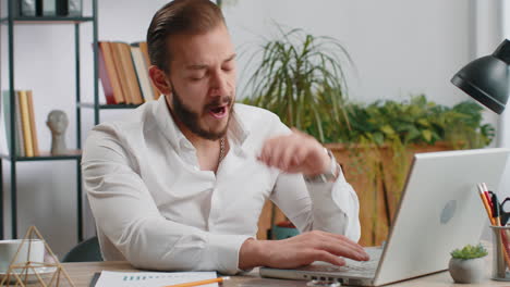 Bored sleepy business man worker working on laptop computer yawning falling asleep at home office