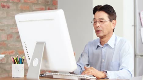 Asian-businessman-using-computer-at-desk