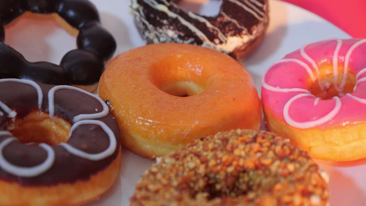 deliciosas rosquillas de diferentes colores en un plato blanco con fondo rojo.