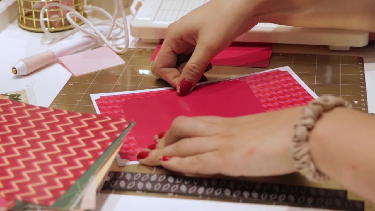 Female hands gluing red festive paper for handmade christmas wish card
