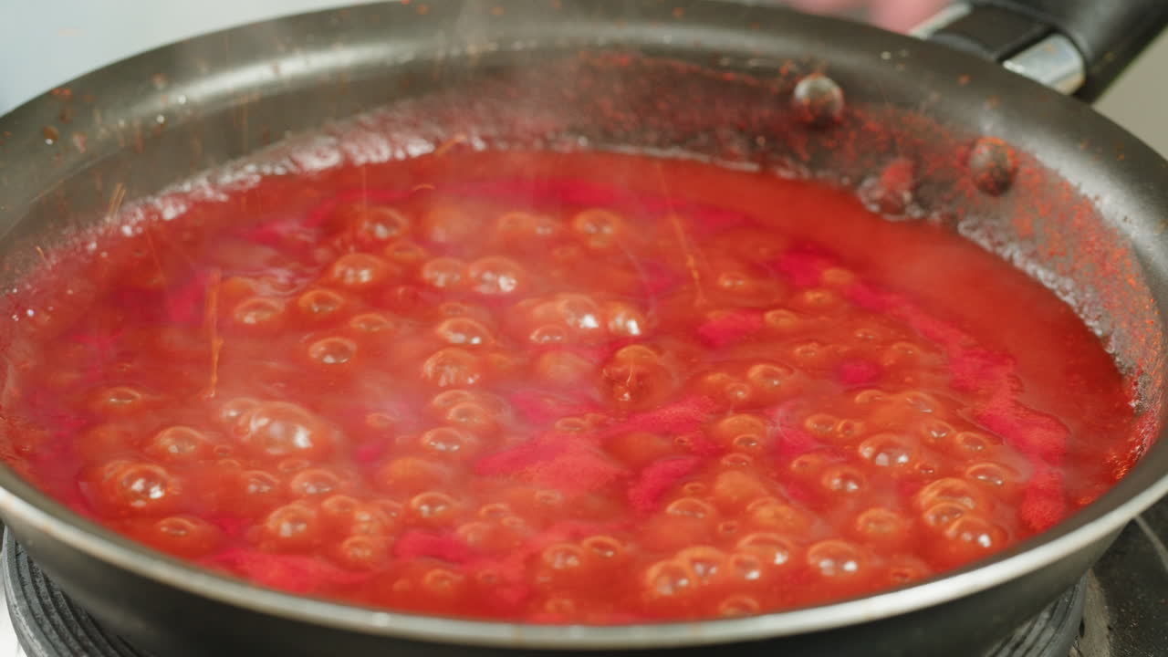 Chicken in tomato sauce is boiling on a frying pan with spices. Cooking tomato sauce curry with chicken fillet. Traditional Italian Mexican Asian dish. High quality studio shot for cafe, restaurant close up.