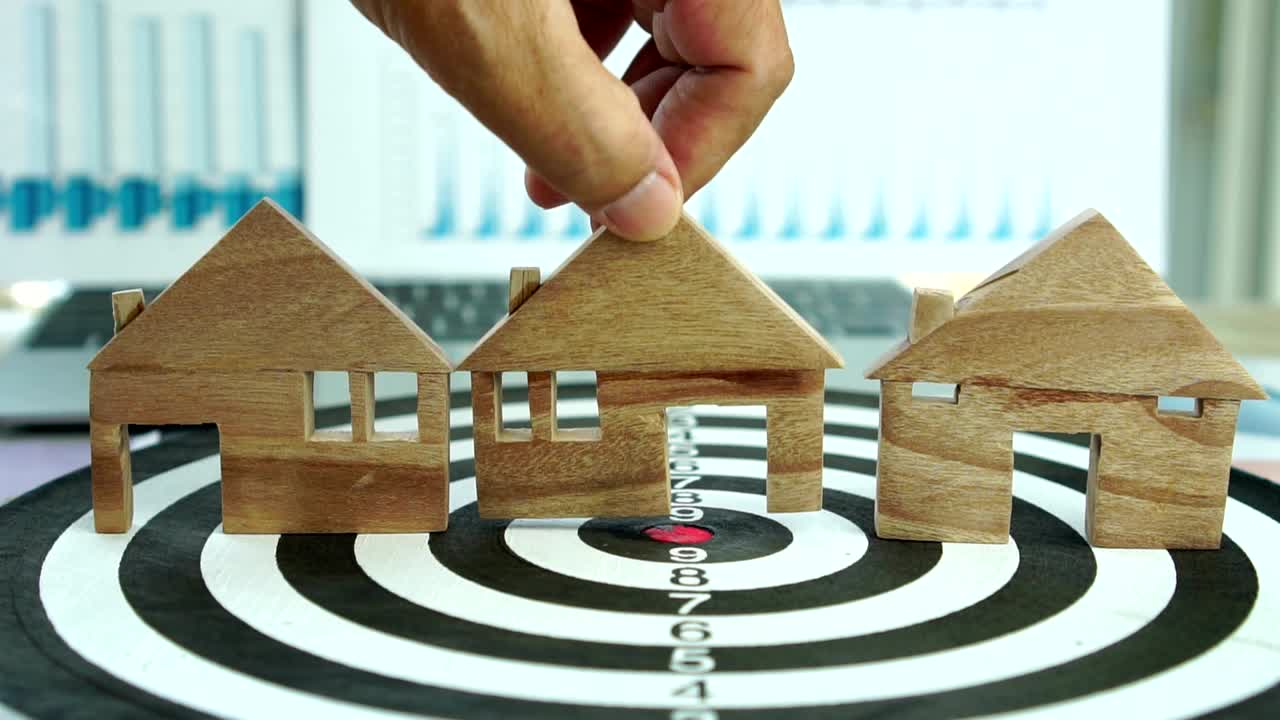 다트보드에서 집 모델을 손으로 선택하십시오. 집을 구입하기 위해 모기지 투자 자산 사업을 선택하고 돈을 절약하는 개념.