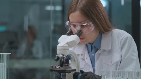 Experto-Forense-Está-Probando-Evidencia-En-El-Laboratorio-Viendo-Muestras-En-El-Microscopio.-Una-Técnica-Femenina-Está-Investigando-El-Análisis.-Retrato-De-Una-Mujer-En-El-Laboratorio.