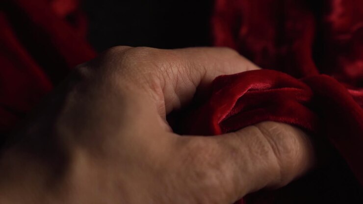 A mans hand touching red material and crushing it in anger