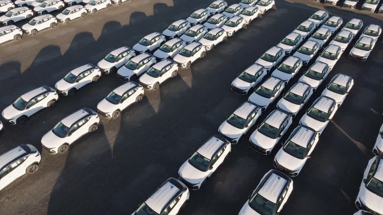 Aerial - identical cars parked at manufacturing plant parking lot