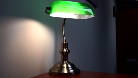 green reading lamp stands on a brown desk in a luxurious bedroom