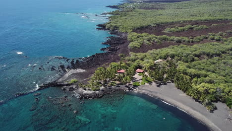 Vista-Aérea-De-La-Playa-De-Arena-Negra-En-La-Isla-Grande,-Hawaii-Bordeada-De-Palmeras-Y-Rocas-De-Lava