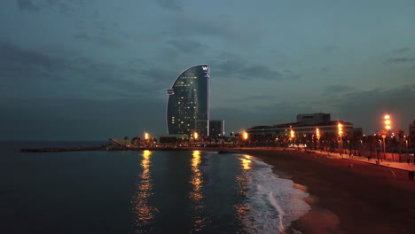 Vista-Aérea-De-La-Costa-De-Barcelona,-España-Con-El-Hotel-W-Al-Fondo-Durante-La-Noche