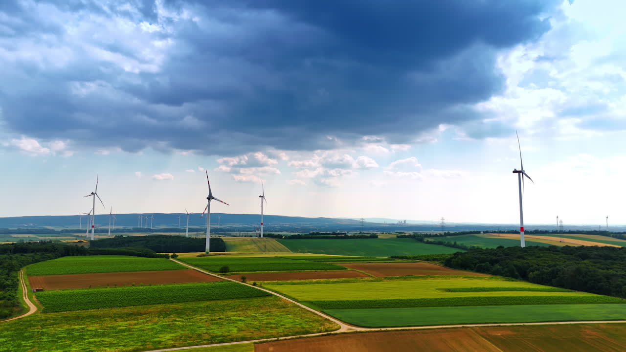 Wind turbines surrounded by green fields. Expansive view of wind turbines in a rural setting under a partly cloudy sky