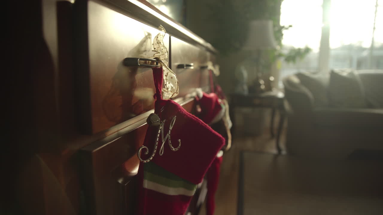 muñeco lento en medias navideñas colgando de la cómoda con el sol entrando por la ventana creando destellos de lente