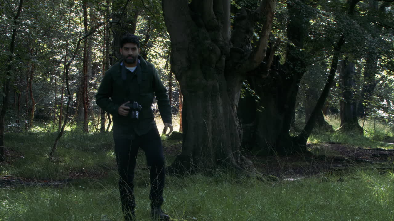 Male Photographer Walking And Taking Photos In Woodland Forest