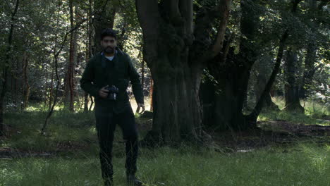 male photographer walking and taking photos in woodland forest