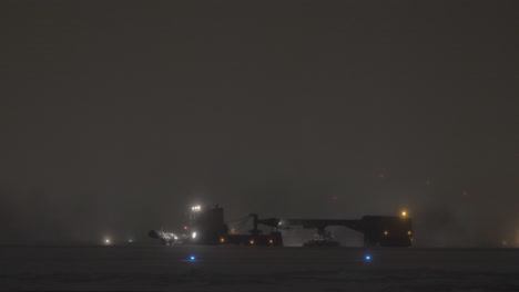 snow plough cleaning runway in airport at night