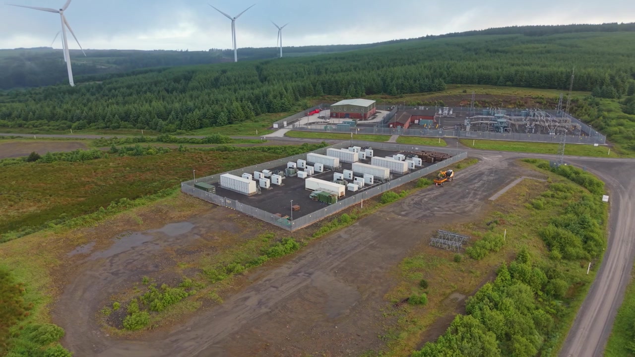 Wide View of BESS Battery Energy Storage System with nearby Electrical Substation near Wind Farm.