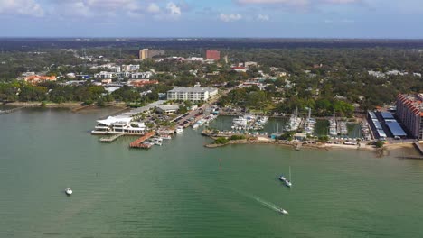 drone footage over downtown dunedin, florida marina with boats and the gulf of mexico and tampa bay