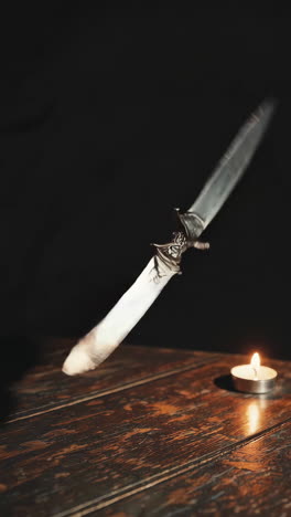 floating knife on wooden table with candle
